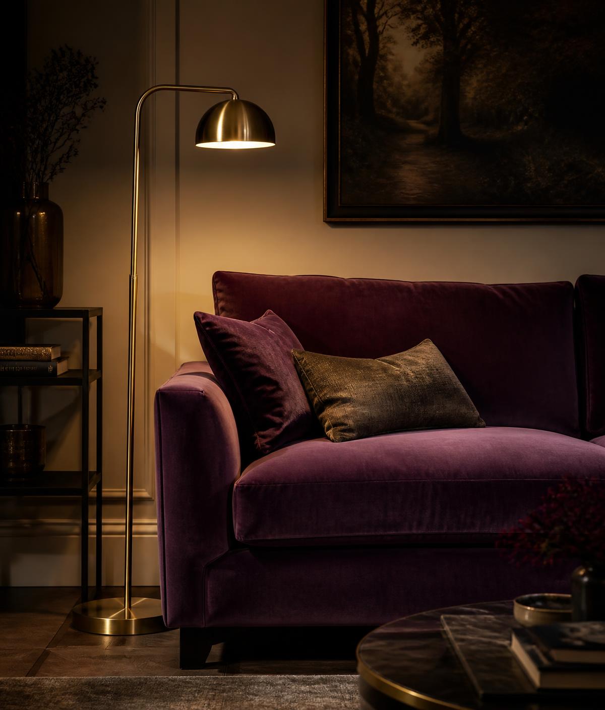 Plush plum velvet sofa with brass floor lamp in a moody evening interior